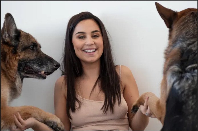 Anna Abreau valokuvattuna kahden koiran kanssa.